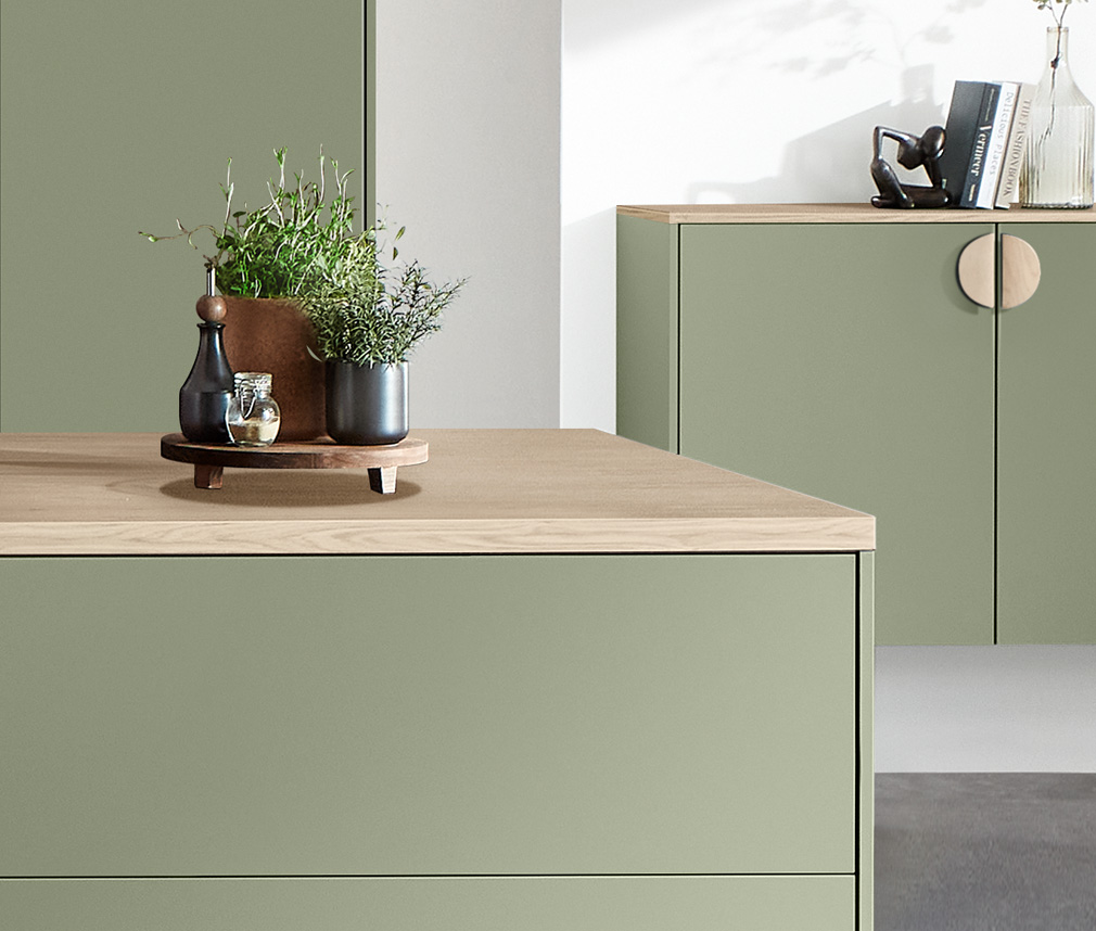 Grönt kök med bänkskivor och handtag i ek